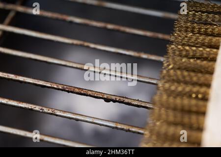 Nahaufnahme des fettigen Grillrostes. Ein Teil einer Bürste mit Messingborsten liegt auf der Seite. Speicherplatz kopieren. Stockfoto