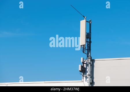 Mobilfunk-Signal-Repeater-Antenne auf der Oberseite des Industriegebäudes mit blauem Himmel als Kopierraum montiert Stockfoto