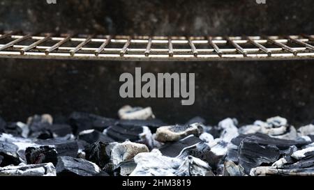 Glühende Holzkohle und Grillrost sind für das Kochen bei Temperatur. Nahaufnahme. Vorderansicht. Stockfoto