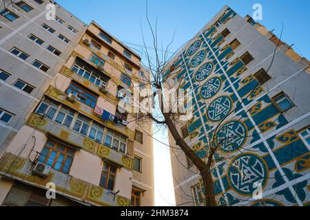 Sowjetische, russische, UdSSR, CCCP-Ära riesige Wandmalereien mit Mosaikfliesen an den Enden eines großen Mehrfamilienhauses. In Taschkent, Usbekistan. Stockfoto