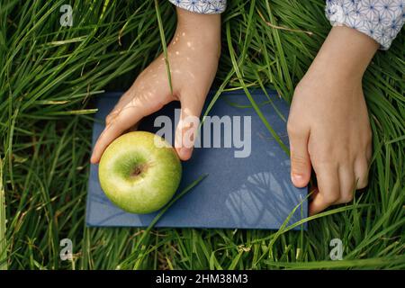 Nahaufnahme Hände halten einen Apfel und ein Buch. Bildungskonzept. Stockfoto