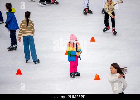 Schlittschuhlaufen für Kinder auf einer Eislaufbahn im Freien. Stockfoto