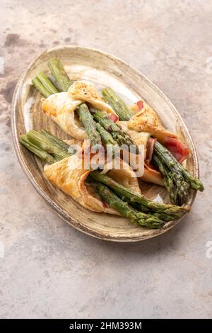 Gebackener grüner Spargel mit Schinkenspeck und Käse in Blätterteig Stockfoto