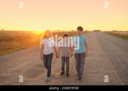 Kinder gehen auf die Straße, um den Sonnenuntergang zu beobachten. Freiheit, Bewegung, Einsamkeit, Demut Konzept. Stockfoto