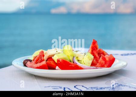 Traditioneller griechischer Salat auf einem Tisch in der Taverne am Meer. Kreta, Griechenland. Selektiver Fokus Stockfoto