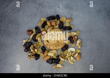 Frisch gebackene gesunde Plätzchen mit Nüssen und Rosinen auf grauem Hintergrund Stockfoto