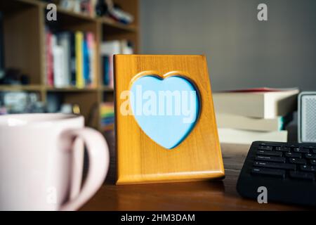Herzförmiger Bilderrahmen aus Holz auf einem Arbeitstisch Stockfoto