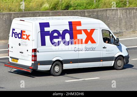 FedEx rot-blaues Firmenlogo auf der Seitenrückseite der grenzüberschreitenden Paketzustellung Lieferwagen und Fahrer, die auf der britischen Autobahn unterwegs sind Stockfoto