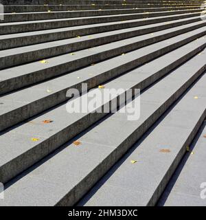 Nahaufnahme Geradlinige lange breite Steintreppen bei Sonnenschein Steigen im Schatten auf Stufen in der City of London besprengte herbstliche Blätter England UK Stockfoto