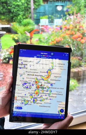 Echtzeit-Farbradar ipad App-Daten zeigt Niederschläge auf der lokalen Karte Frau wartet auf nasses Wetter auf Home-Fenster klar zurück zu Garten Essex UK Stockfoto