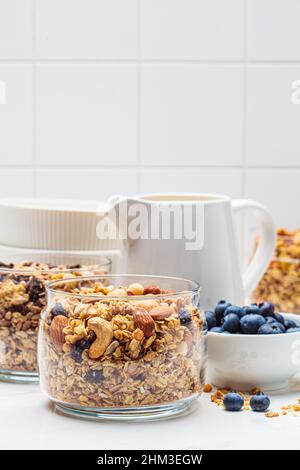 Verschiedene Arten von hausgemachtem Müsli (Obst, Nüsse und Schokolade) in Gläsern auf einem weißen Küchentisch. Frühstücksangebot. Stockfoto