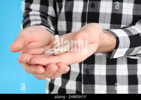 Junger Mann mit Hörgerät auf blauem Hintergrund Stockfoto