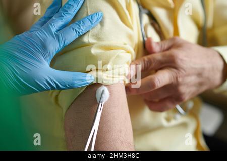 Krankenschwester, die nach der Injektion eines Impfstoffs gegen einen neuen Stempel des Coronavirus einen Wattebausch vor Ort einsetzte Stockfoto