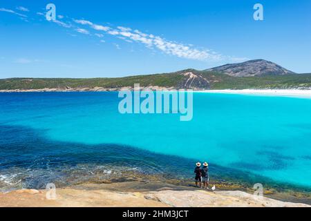 Zwei Personen beobachten eine Gruppe von Delfinen an der berühmten Hellfire Bay, Cape Le Grand, in der Nähe von Esperance, Western Australia, WA, Australien Stockfoto