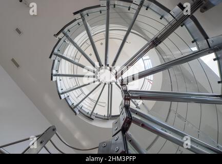 Modernes Interieur des luxuriösen Privathauses. Wendeltreppe aus Glas und Metall. Ansicht von unten. Stockfoto