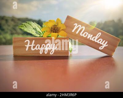 Happy Monday Text auf Holzblöcken mit gelber Blume und Naturhintergrund. Motivationskonzept. Stockfoto