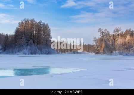 Winterlandschaft am Morgen auf dem Fluss mit türkisfarbenem Eis. Mündung des Flusses der Stadt in Südjakutien, Russland Stockfoto