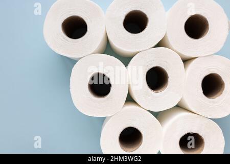 Frische, neue weiße Toilettenpapierrollen auf blauem Hintergrund. Konzept für persönliche Hygiene und Gesundheitsprobleme. Draufsicht, Kopierbereich Stockfoto