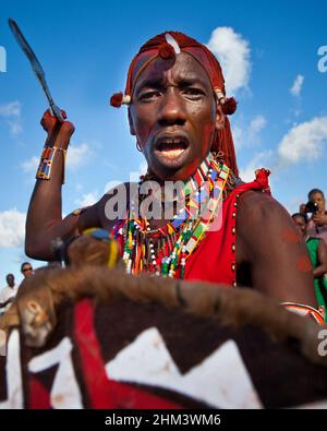 Der Maasai-Krieger aus dem kenianischen Kontingent schwingt bei einer Straßenaufführung beim Karneval auf den Seychellen einen Speer. Stockfoto