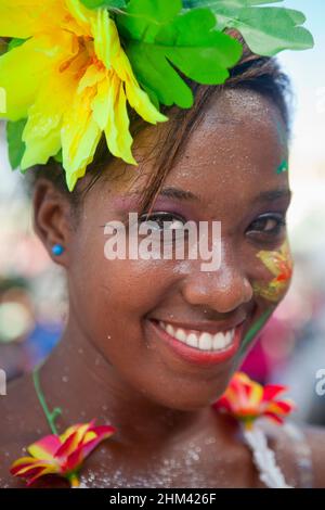 Porträt einer jungen Frau, die lächelt und eine Blumengirlande trägt, während sie während des Karnevals auf den Seychellen auf der Straße auftrat. Stockfoto