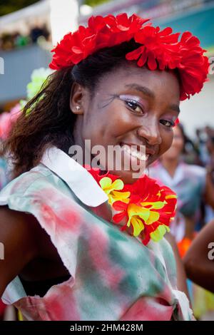 Porträt einer jungen Frau, die lächelt und eine Blumengirlande trägt, während sie während des Karnevals auf den Seychellen auf der Straße auftrat. Stockfoto