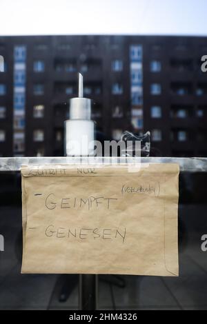 07. Februar 2022, Hamburg: Ein Schild mit der Aufschrift "nur Eintritt - geimpft (komplett) - geneselt" hängt im Fenster eines Cafés im Stadtteil Hamburg-Veddel. Foto: Christian Charisius/dpa Stockfoto