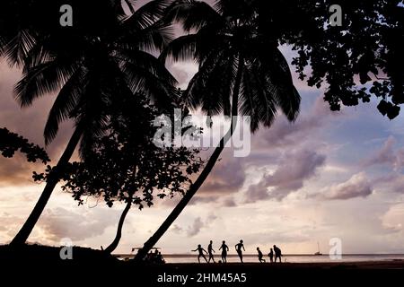 Silhouetten am Strand von Beau Vallon spielen Fußball bei Sonnenuntergang auf Mahe Island, Seychellen. Stockfoto