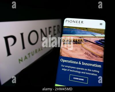 Person, die Smartphone mit Webseite des US-Unternehmens Pioneer Natural Resources Company auf dem Bildschirm mit Logo hält. Konzentrieren Sie sich auf die Mitte des Telefondisplays. Stockfoto