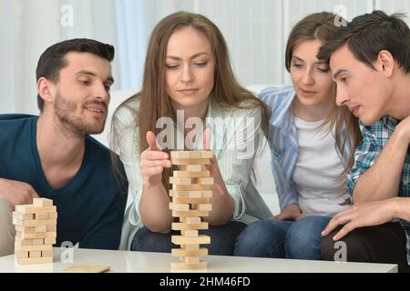 Männer und Frauen sitzen am Tisch und spielen mit Holzblöcken Stockfoto