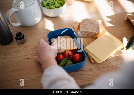 Nahaufnahme der Mutter, die in der Küche zu Hause einen Snack zur Lunchbox zubereitet. Stockfoto