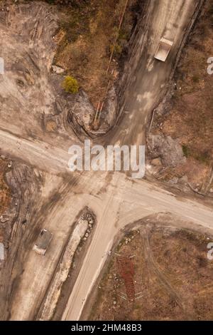 Muldenkipper auf Granit Steinbruch Bergbau Anlage Luft. Lastwagen mit Granitfelsen auf einer Straße von einer Drohne beladen Stockfoto