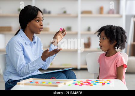 Logopädin, die mit einem kleinen schwarzen Mädchen arbeitet Stockfoto