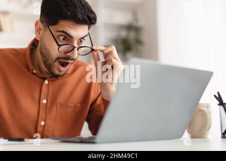 Verwirrt Araber Kerl mit Laptop Blick auf den Bildschirm Stockfoto