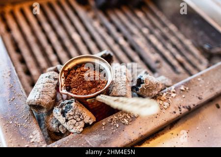 Brauen eines türkischen Kaffees in brassem Cezve auf einem Kohleofen in traditioneller Methode in einer Straße von Istanbul, Türkei Stockfoto