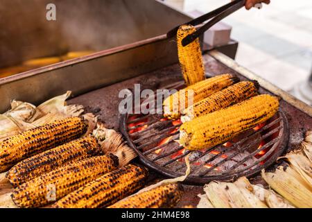 Straßenverkäufer, der Misir auf einem Kohlegrill in Istanbul, Türkei, röstet. Misir, ein beliebtes türkisches Straßenessen, ist ein frisch gekochter oder gegrillter Mais auf t Stockfoto