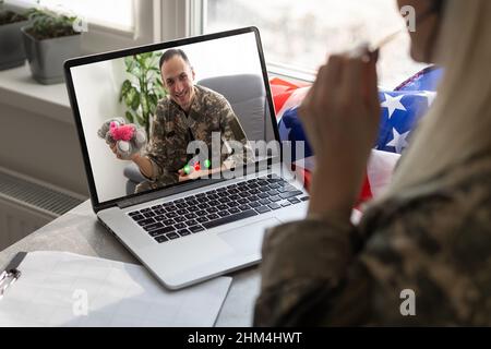 Reifer männlicher Soldat, der im Hauptquartier einen Laptop für die Kommunikation mit seiner Familie verwendet. Stockfoto