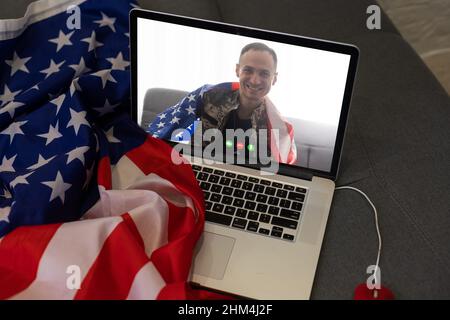Reifer männlicher Soldat, der im Hauptquartier einen Laptop für die Kommunikation mit seiner Familie verwendet. Stockfoto