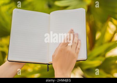 Frauenhände in einem tropischen Hintergrund Namensschild, Zeichnung Block, Papier, mockup Stockfoto