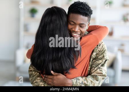 Homecoming-Konzept. Glücklicher Schwarzer Soldat Mann Umarmt Frau Nach Dem Zurückkehren Nach Hause Stockfoto