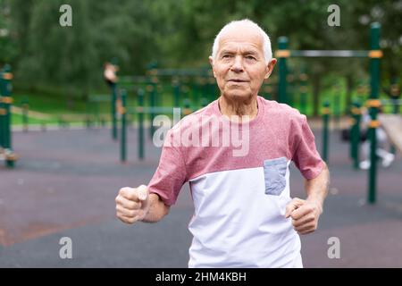 Sportlicher älterer Mann mit grauen Haaren läuft im Park Stockfoto