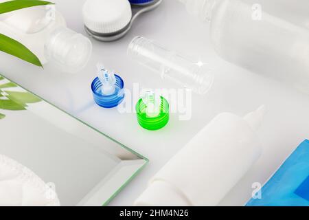 Kontaktlinsen-Kit mit Flasche Linsenlösung, Behälter, Koffer und Augentropfen auf einem weißen Tisch. Das Konzept der richtigen Verwendung von Kontaktlinsen und Nachtlinsen A Stockfoto