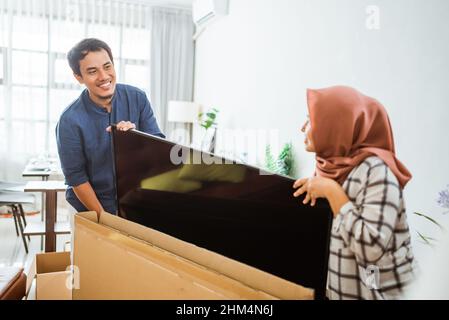 Aufgeregt paar Einrichten von neuen Fernseher zu Hause Stockfoto