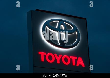 Batumi, Georgia - Januar 26 2022: Nahaufnahme des Toyota-Händlerlogos, das abends vor einem dunkelblauen Himmel beleuchtet wird Stockfoto