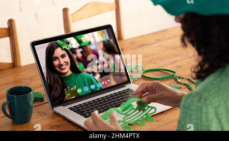 Kaukasische Frau, die eine Schamrock-Brille hält, während sie zu Hause einen Videoanruf auf dem Laptop führt Stockfoto