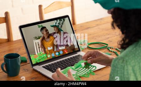 Kaukasische Frau, die eine Schamrock-Brille hält, während sie zu Hause einen Videoanruf auf dem Laptop führt Stockfoto