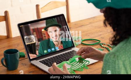 Kaukasische Frau, die eine Schamrock-Brille hält, während sie zu Hause einen Videoanruf auf dem Laptop führt Stockfoto