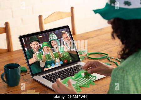 Kaukasische Frau, die eine Schamrock-Brille hält, während sie zu Hause einen Videoanruf auf dem Laptop führt Stockfoto