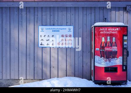 Erfrischen Sie sich jetzt eiskalt, der Werbeslogan auf einem Coca Cola-Automaten am Eibsee, Zugspitze. Schnee liegt vor dem Automaten. Stockfoto