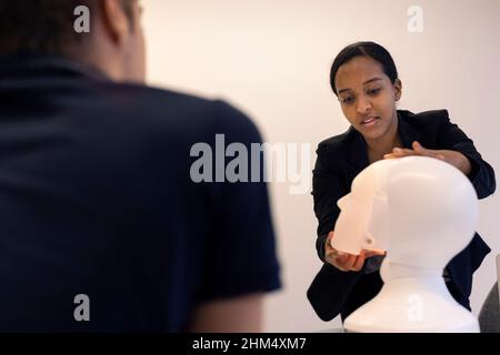 Geschäftsleute diskutieren während des Meetings über den Roboter-Sprachassistenten Stockfoto