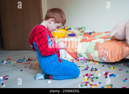 Das Kind spielt allein in seinem Schlafzimmer mit farbigen Mauergliedern Stockfoto